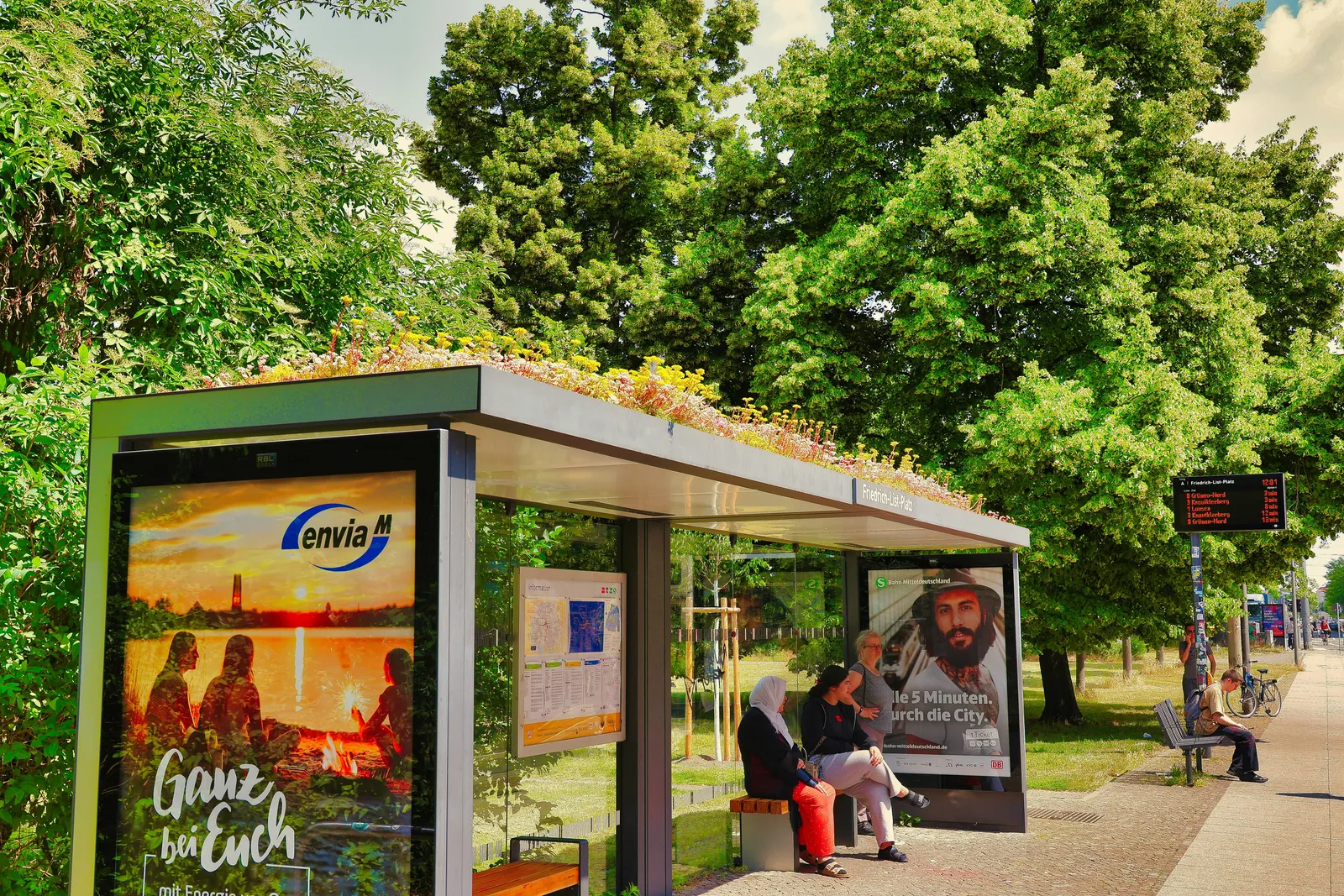 Abribus vitré avec panneaux publicitaires, voyageurs assis et passant dans l’espace urbain