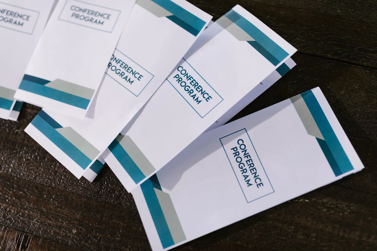 Gros plan sur des brochures de conférence posées à plat, avec dos visibles et reliures apparentes