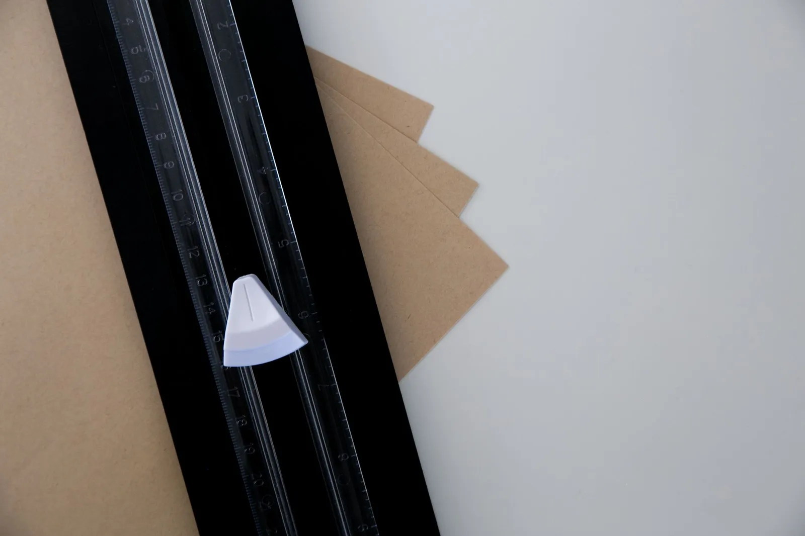 Massicot de bureau coupant une feuille de papier rouge sur un tapis de coupe vert