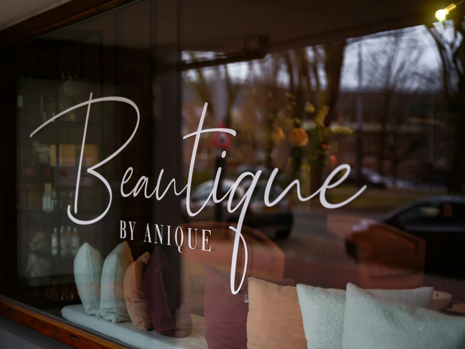 Vitrine vue de face avec lettrage décoratif blanc sur le verre et intérieur de boutique en arrière-plan
